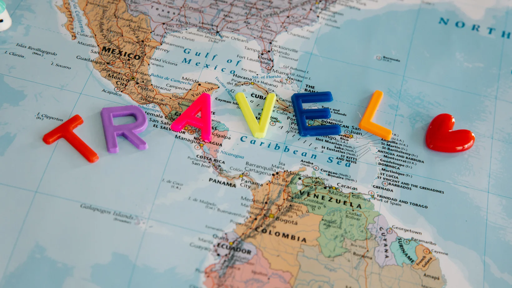Letras de colores formando la palabra Travel sobre un mapa de América Latina